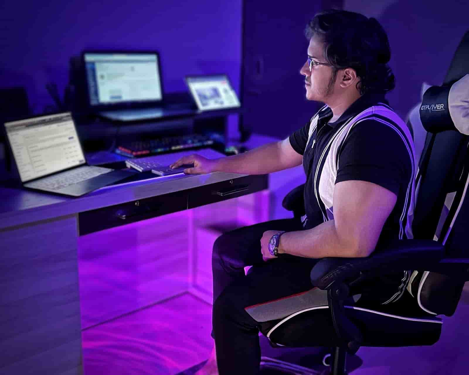 Shakir Azim working at a multi-monitor home office setup, blogging expert and home office consultant.
